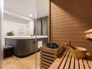 a bathroom with a tub and a shower with a wooden wall at Holiday Home Vuk by Interhome in Kupjak