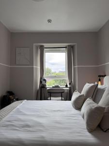 a bedroom with a large white bed with a window at The Glendevon Hotel in Auchterarder
