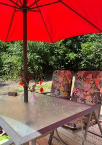 a table with a red umbrella and two chairs at Haus Kanalliebe in Nübbel