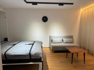 a bedroom with a bed and a couch and a table at Aleksandra Apartment in Ventspils