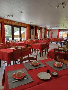 a dining room with red tables and chairs and windows at Hotel et centre de vacances Le Choucas in Sixt