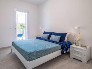 Dormitorio blanco con cama con sábanas azules y ventana en Apartment Alta Marea by Interhome, en Valledoria