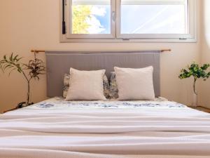un letto con lenzuola e cuscini bianchi sotto una finestra di Holiday Home Inés by Interhome a L'Ampolla