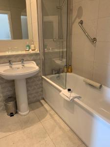 a bathroom with a sink and a shower and a tub and a sink at The Address Cork (formerly Ambassador Hotel & Health Club) in Cork