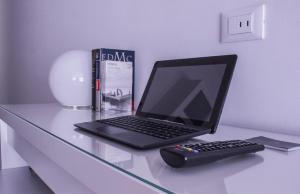 un computer portatile su un tavolo di vetro con un libro e un telecomando di Domus Raffaello a Roma
