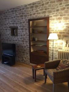 a living room with a couch and a television and a brick wall at Mesnay, belle maison spacieuse in Mesnay