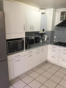a kitchen with white cabinets and a black microwave at Mesnay, belle maison spacieuse in Mesnay
