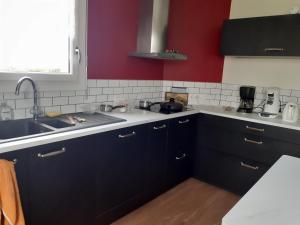 - une cuisine avec des placards noirs et un évier dans l'établissement Chambres chez l habitant, à Langrolay 7 autres photos