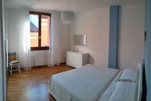 a white bedroom with a bed and a window at Appartamento Le Palmine in Cento