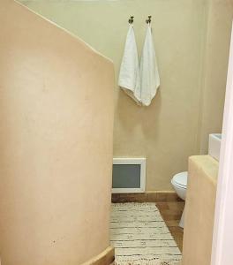 a bathroom with a toilet and towels hanging on the wall at Dar Amina in Sidi Ifni +9 photos
