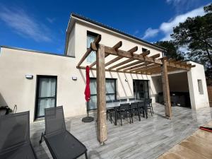 a wooden pergola on a patio with a table and chairs at La Forêt d'Armotte villa 19 in Saint-Augustin