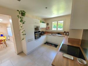 eine Küche mit weißen Schränken und einem Tisch darin in der Unterkunft Magnifique villa piscine clim vue dominante 6 couchages in Saint-Clément-de-Rivière