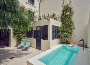 a swimming pool with two chairs next to a building at L'Arlésienne in Arles +2 photos