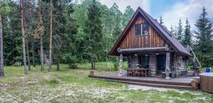 a log cabin in the woods with a wooden deck at Tammeoja puhkemaja in Sõmeru