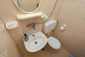 Un baño con inodoro, lavabo y espejo. en Guesthouse Berati, en Berat