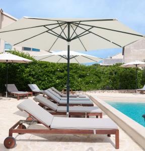 a group of lounge chairs with an umbrella next to a pool at Laura Apartments in Brodarica
