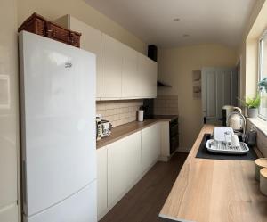 a kitchen with white cabinets and a white refrigerator at Four Bedroom High Spec Victorian Townhouse in Clitheroe