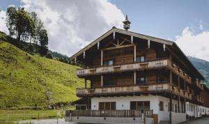 a large wooden building with a balcony on a hill at Wieshofgut in Saalbach-Hinterglemm