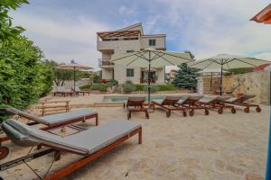 eine Gruppe von Liegestühlen und Sonnenschirmen vor einem Gebäude in der Unterkunft Laura Apartments in Brodarica