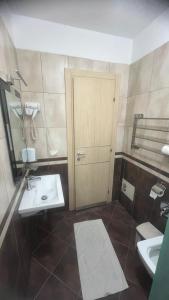 a bathroom with a sink and a toilet and a door at Sunrise Hotel Cameria in Durrës