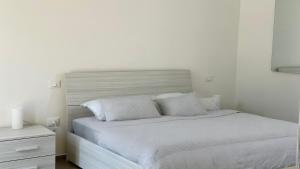 a white bedroom with a bed with white sheets and pillows at SE100 - Senigallia, nuovo bilocale a 100 mt dal mare in Senigallia