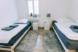 two twin beds in a room with two tables at City Apartment Singen in Singen +4 photos