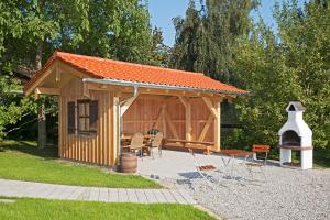 ein Holzschuppen mit Grill und Stühlen in einem Hof in der Unterkunft Thaurerhof Urlaub auf dem Bauernhof in Bernau am Chiemsee