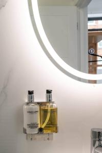 a bathroom with two bottles of soap and a mirror at Stylish comfort in London in Finchley