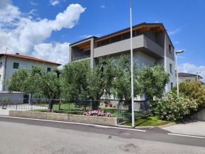 un edificio bianco con alberi di fronte a una strada di Oasi degli Ulivi a Riva del Garda