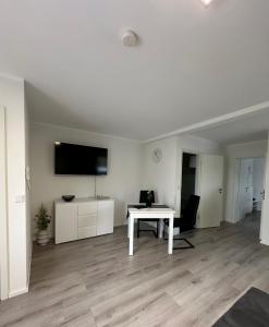a white living room with a white table and a tv at FeWo Talblick in Diemelsee