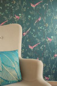 a chair in front of a wall with bird wallpaper at Les Villas Chamontines - La Villa des Chênes in Labeaume +58 photos