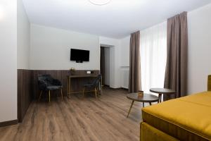 una camera d'albergo con letto, scrivania e TV di Hotel Sole - Sonne a Dobbiaco