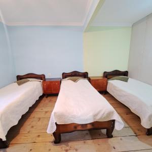 three beds in a room with wooden floors at Chvibiani Guesthouse & Bar in Ushguli