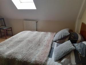 - une chambre dotée d'un lit avec une couverture et des oreillers dans l'établissement Chambres chez l habitant, à Langrolay