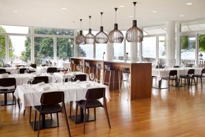 ein Restaurant mit weißen Tischen, Stühlen und Fenstern in der Unterkunft Hotel Boldern in Männedorf