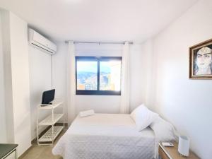 a white bedroom with a bed and a window at Apartamento con piscina, urbanización privada by AlohaPalma in Águilas +6 photos