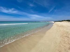 a sandy beach with the ocean and the sky at Le tre coccinelle in Porto Cesareo