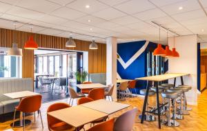 a restaurant with tables and chairs and a blue wall at ibis budget Leicester in Leicester
