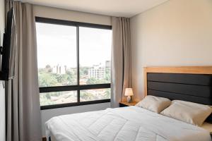 Un dormitorio con una cama y una ventana grande. en Excelente Depto en Las Lomas, en Asunción