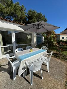 a white table with two chairs and an umbrella at La Maison des Vacances in Dolus d'Oléron
