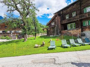 a group of chairs sitting in the grass in front of a house at Apartment Kröll beim Geislerhof by Interhome in Ramsau