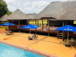 a resort with chairs and umbrellas and a swimming pool at Falcon Lodge (ET) in Bela-Bela