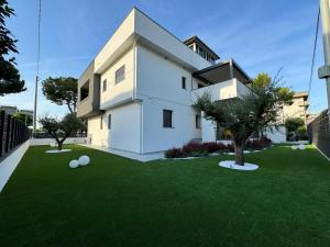 a white house with a green yard with trees at B&B Room47 in Alba Adriatica