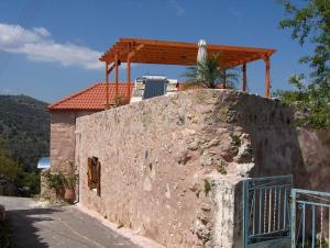 a house with a wooden roof on top of a wall at Charmante maison crétoise à Embrosneros in Embrósneros