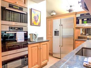 a kitchen with wooden cabinets and a stainless steel refrigerator at Holiday Home Chalet Rebhalde by Interhome in Schönried