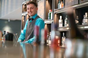 a man is standing behind a counter in a bar at Motel One Lübeck in Lübeck