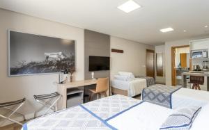 Habitación de hotel con 2 camas y escritorio en Villary Flats Gramado, en Gramado