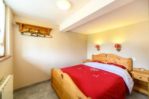 a bedroom with a wooden bed with red sheets at Chalet La Sportive in Cornimont