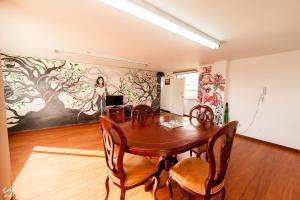a dining room with a table and chairs and a painting at North House Hostel in Bogotá