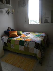 a bed in a room with a quilt on it at Apartamento Chile in Guarujá